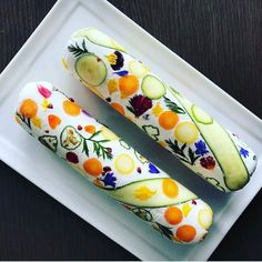 two slices of cucumber on a plate with flowers and leaves painted on them