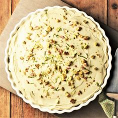 a pie sitting on top of a wooden table next to a knife and spoons