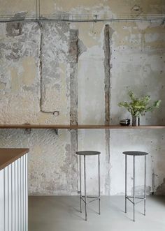 three stools are in front of a wall with exposed plaster and metal barstools