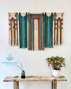 a wooden table topped with a potted plant next to a wall hanging