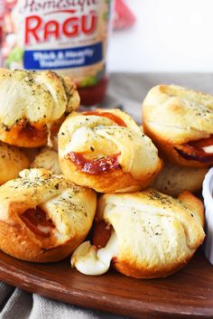 hotdogs with cheese and ketchup on a wooden plate next to a jar of mayonnaise ragu