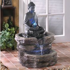 a buddha statue sitting on top of a stone fountain