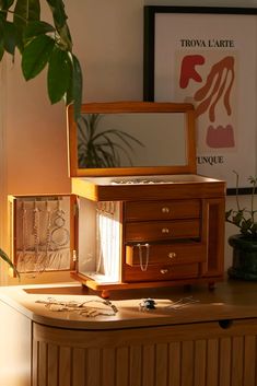 an open jewelry box sitting on top of a table next to a potted plant