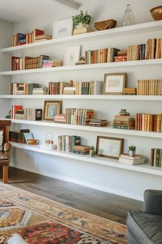 a living room filled with lots of books on top of white shelving unit units