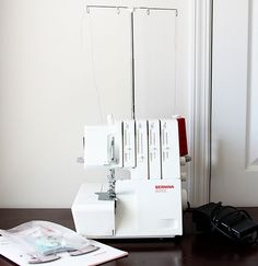 a sewing machine sitting on top of a wooden table next to a book and bag