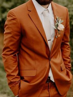 a man in an orange suit and white shirt wearing a flower boutonniere