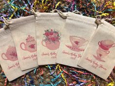 three tea bags with pink designs on them sitting on top of confetti sprinkles