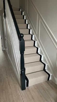 a staircase with black railing and white carpet