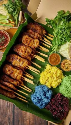 an assortment of food is displayed in a box on a wooden table, including skewers and sauces