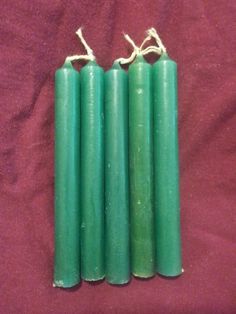 four green candles sitting on top of a red cloth