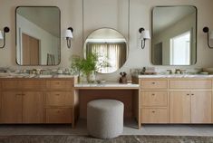 a bathroom with two sinks, mirrors and a stool in front of the sink area