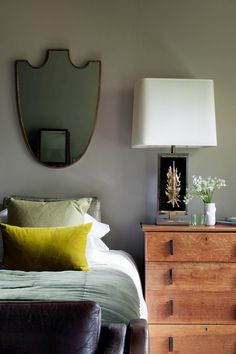 a bed sitting next to a wooden dresser under a mirror on top of a wall