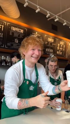 two women in green aprons are serving coffee to each other at a restaurant counter