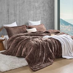 a bedroom with a large bed covered in brown and white comforters, pillows and blankets