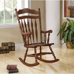 a wooden rocking chair sitting on top of a hard wood floor next to a window