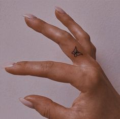 a person's hand with a small tattoo on it, holding up their fingers