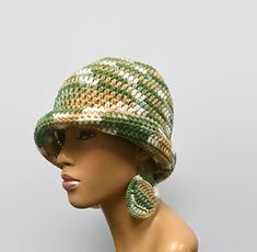 a mannequin head wearing a green and white knitted hat with ear clips