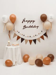 a birthday party with balloons, cake and bunting banner on the wall in front of it