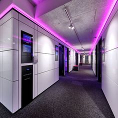 an empty hallway with white walls and purple lighting