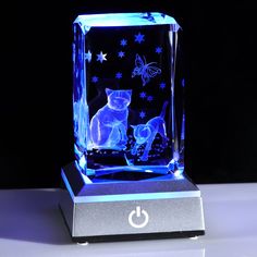 an illuminated cat and dog figurine sitting on top of a silver base with blue lights