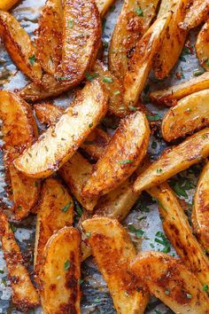 fried potatoes with herbs and seasoning sitting on a sheet of parchment paper, ready to be eaten