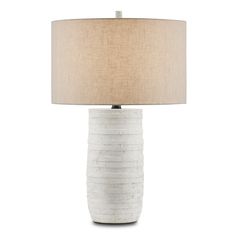 a white ceramic table lamp with a beige shade on the base and a light brown drum