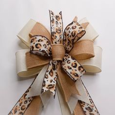 a leopard print bow on a white background with brown and tan ribbon around the bow