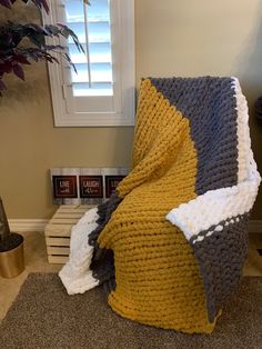 a blanket that is sitting on the floor next to a potted plant and window