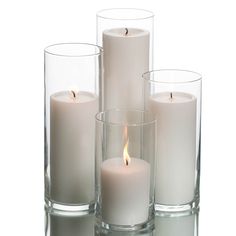 three white candles are in glass vases