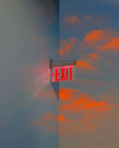 a red exit sign hanging from the side of a wall under a cloudy blue sky