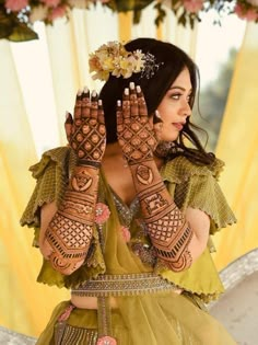 a woman with henna on her hands and flowers in her hair is posing for the camera