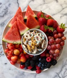 a white plate topped with fruit and pretzels next to watermelon slices