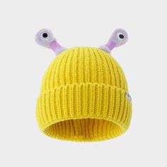 a yellow knitted hat with two eyes on the front and one eye at the back