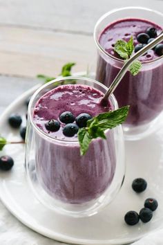 two glasses filled with blueberry smoothie on a white plate