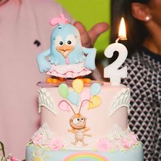 a birthday cake decorated with an image of a bird on top and the number two candle is lit