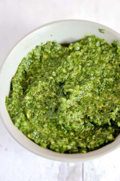 a white bowl filled with green sauce on top of a table