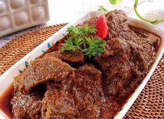 a close up of a plate of food with meat and vegetables in sauce on a table