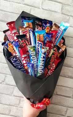 a person holding a bag full of candy and candies in their hands on a brick wall