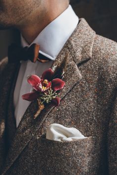 a man wearing a suit and bow tie with a boutonniere on his lapel