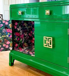 a green cabinet with flowers painted on the front and side panels is sitting on a hard wood floor