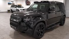 a black land rover is parked in a showroom with other cars behind the vehicle