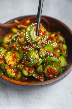 a wooden bowl filled with green vegetables covered in sesame seeds