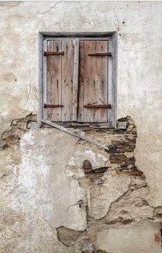 an old window with wooden shutters on the side of a building