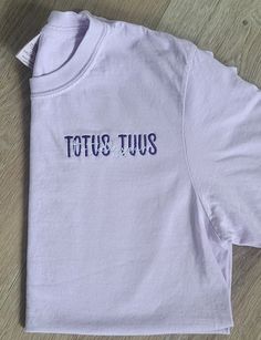 "This Listing is for our Totus Tuus, Totally Yours, embroidered Catholic t-shirt. It is a beautiful Marian t-shirt; in Latin, the phrase, \"Totus Tuus,\" means \"totally yours\", a motto from JPII, who had a great devotion to our blessed Mother.  When placing your order, in the personalization box, please include the following information: 1.) Two Thread colors (one for \"TOTUS TUUS\" and one for \"Totally Yours\" If no thread color is entered, we will automatically use colors as shown in the sa Catholic T Shirt, Casual Short Sleeve Shirt With Letter Embroidery, Purple Cotton Tops With Embroidered Text, Pocket Oratory, Catholic Tshirt, Catholic Clothing, Catholic Shirt, Catholic Tshirts, Minimalist Shirts