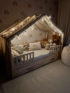 a child's bed with teddy bears in it and lights strung from the ceiling