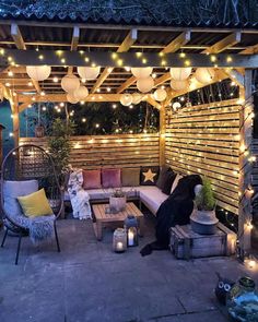 an outdoor seating area is lit up with string lights, lanterns and other decorative items