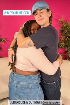 two people hugging each other in front of a pink wall