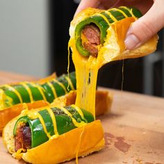 a person is taking a hot dog roll out of the oven with cheese and jalapenos