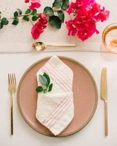 a place setting with pink flowers and goldware