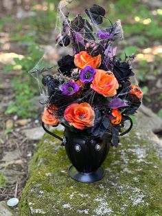 a vase filled with flowers sitting on top of a moss covered rock